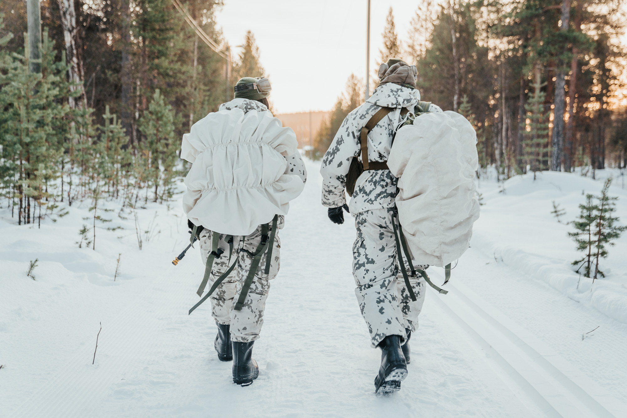 Kaksi rajajääkäriä kävelemässä, auringonlasku taustalla