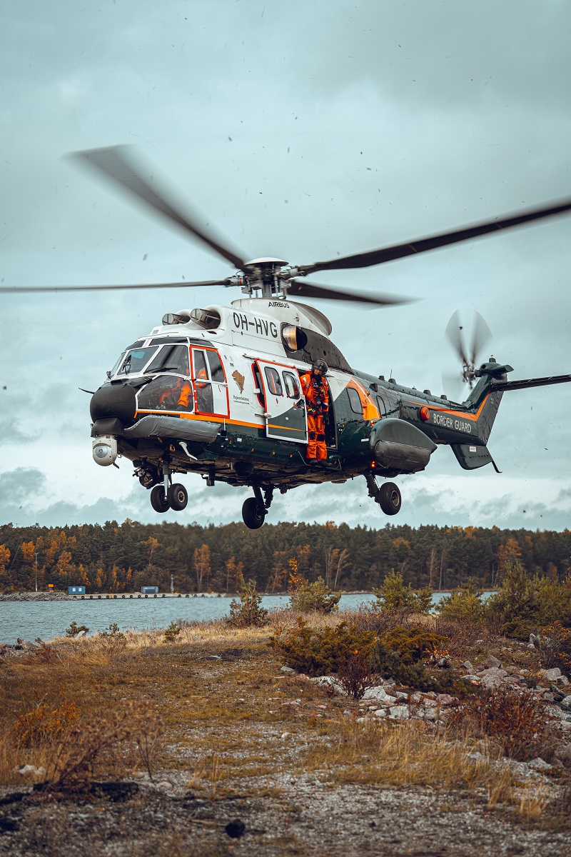 Helikopteri leijailemassa juuri ja juuri maanpinnan yllä.