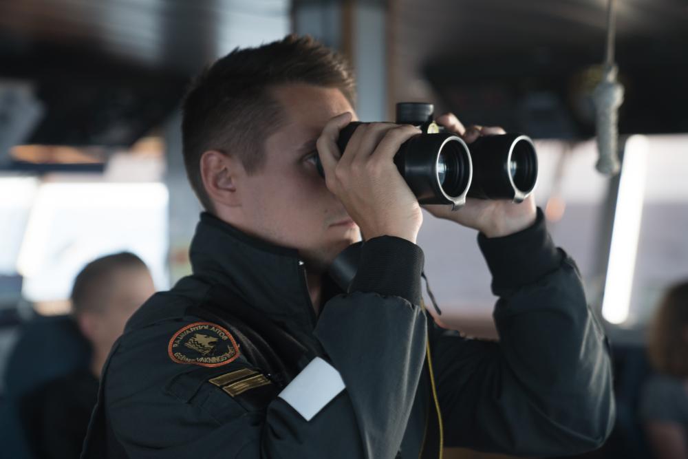 Sjöbevakare tittat med kikare på kustbevakningsfartyg. 