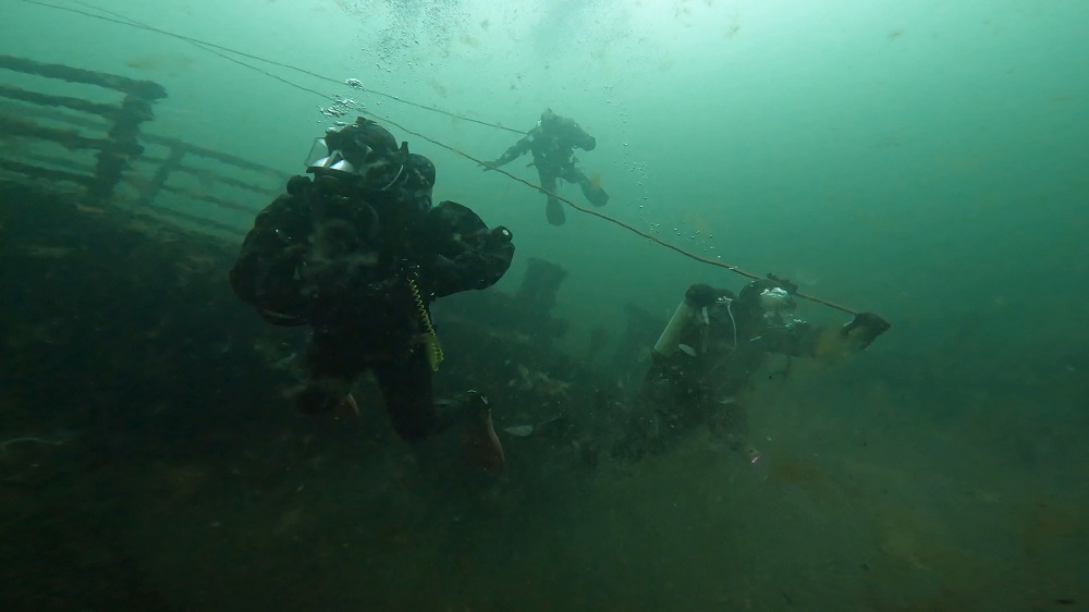 Dykare arbetar under grönt vatten.