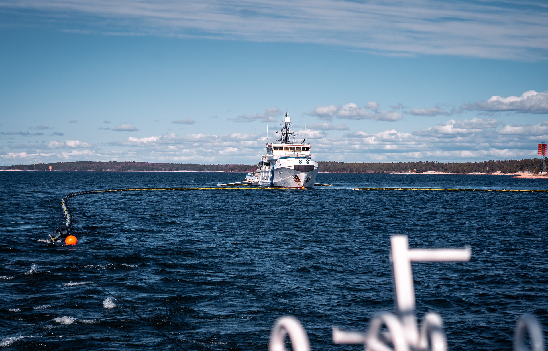 En vit båt på havet. Det finns oljebekämpningsutrustning på vatten. 