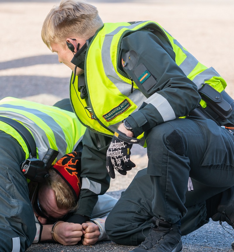 En person ligger på grunden och en annan person är över honom och har en kontroll.