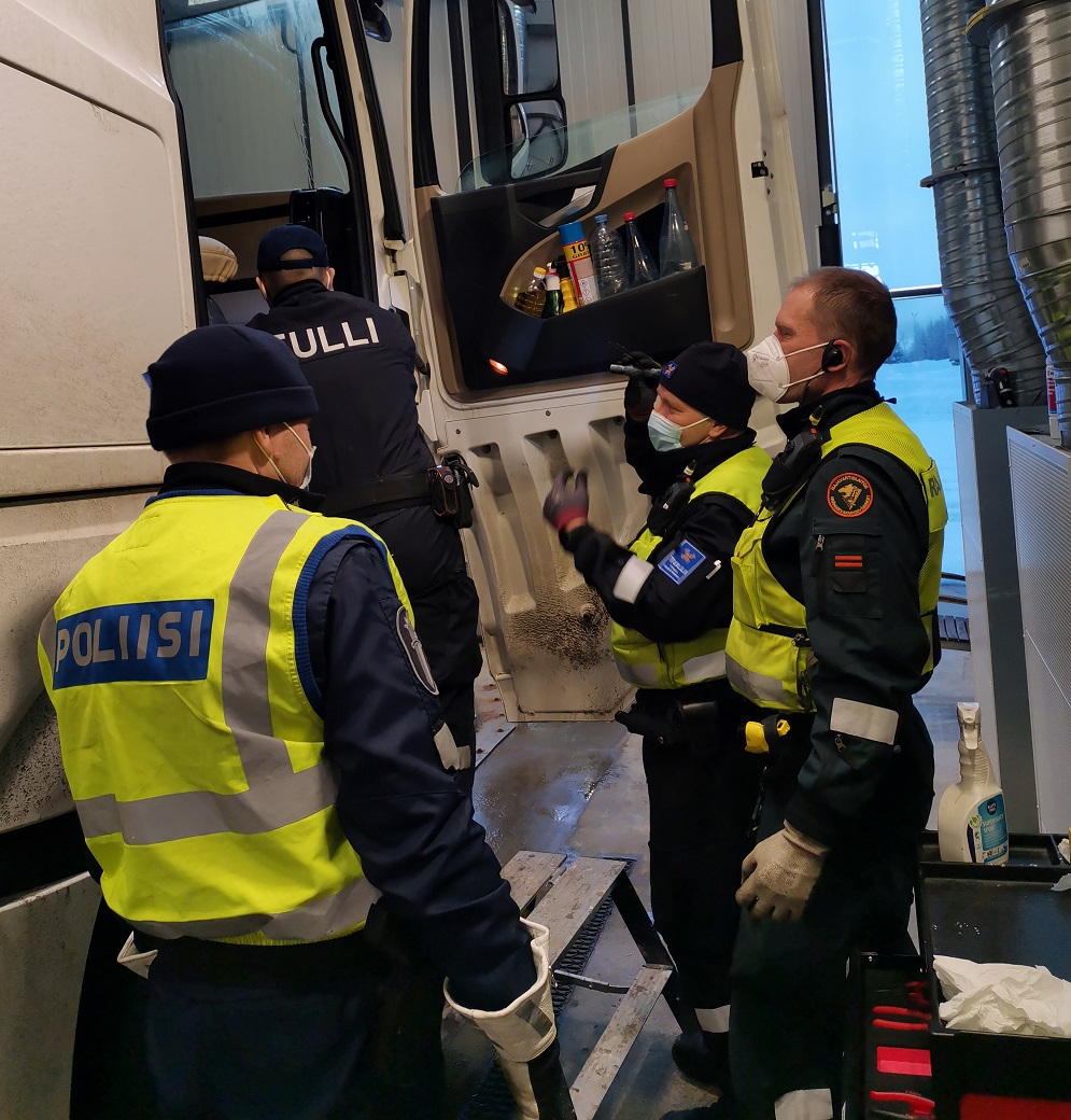 Neljä henkilöä, jotka ovat poliisista, tullista ja rajavartiolaitoksesta, tutkii rekka-autoa.