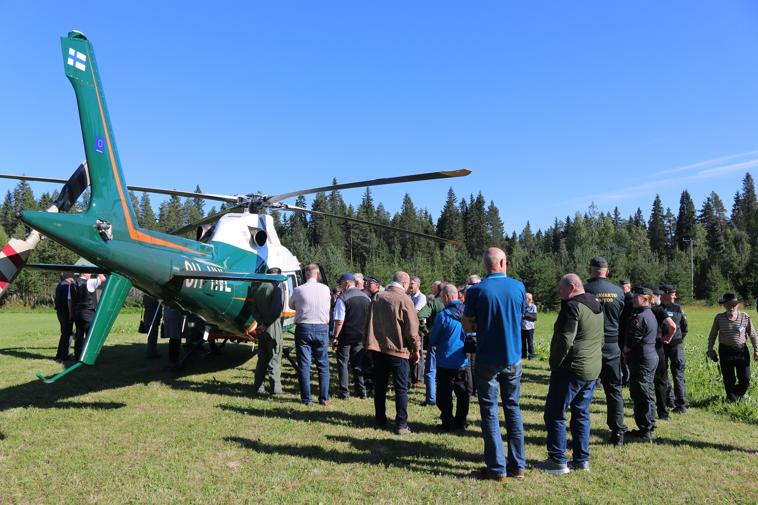 Helikopteri nurmella.Ympärillä paljon ihmisiä.