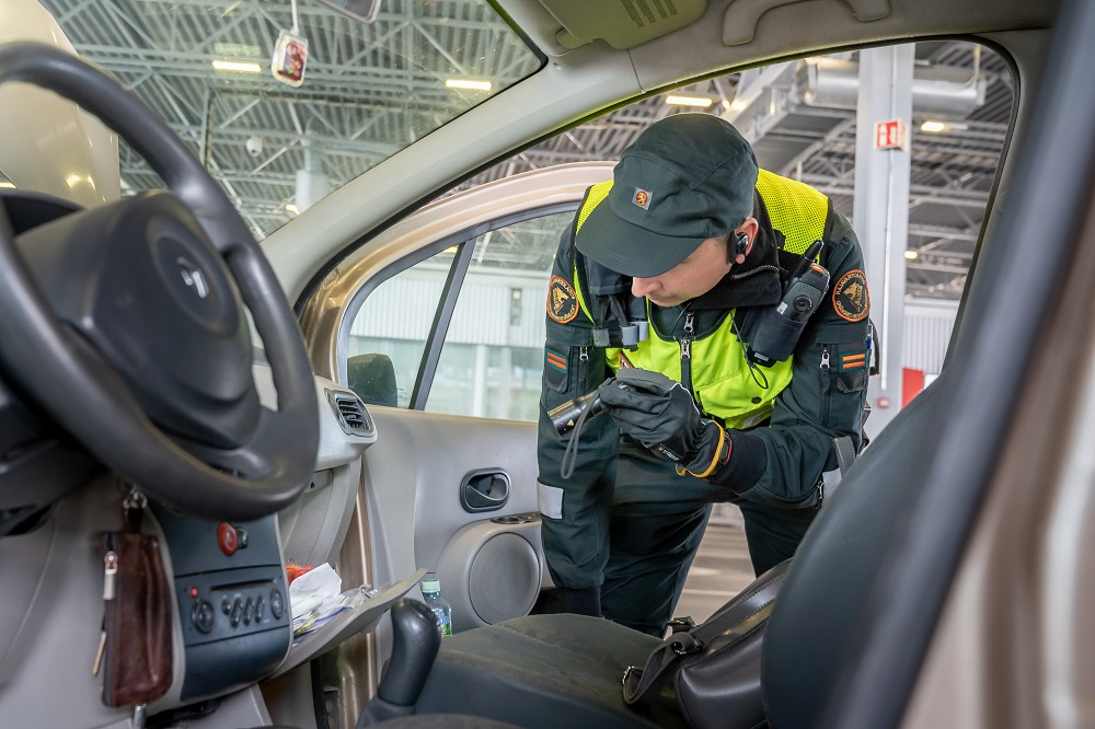 Rajavartija tarkastaa henkilöautoa taskulampun avulla.