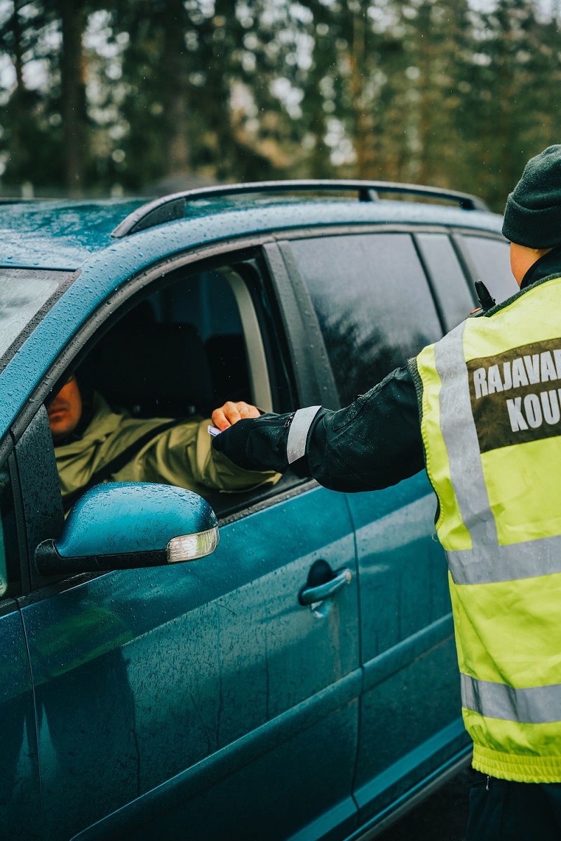 En person stoppar en bil, och föraren ger ut sin körkort.