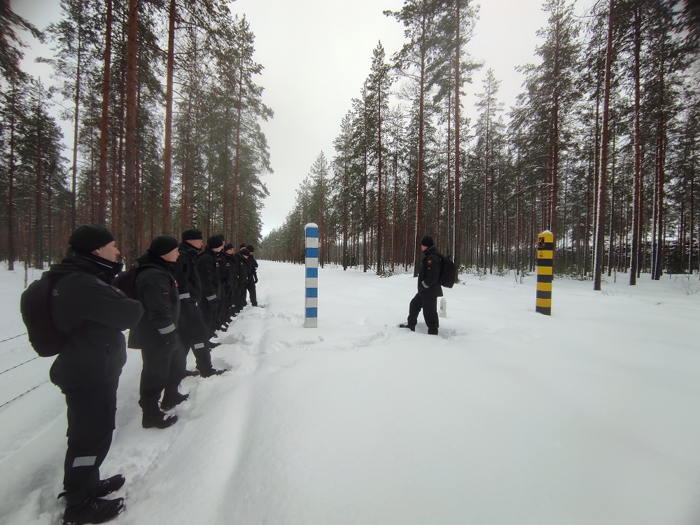 En skog på vinter. Människor står i ett råd.