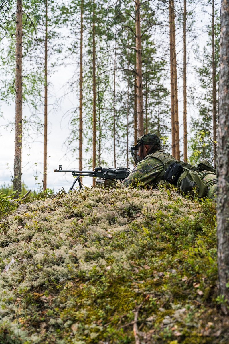 Sotilas metsässä ja tähtää aseella.