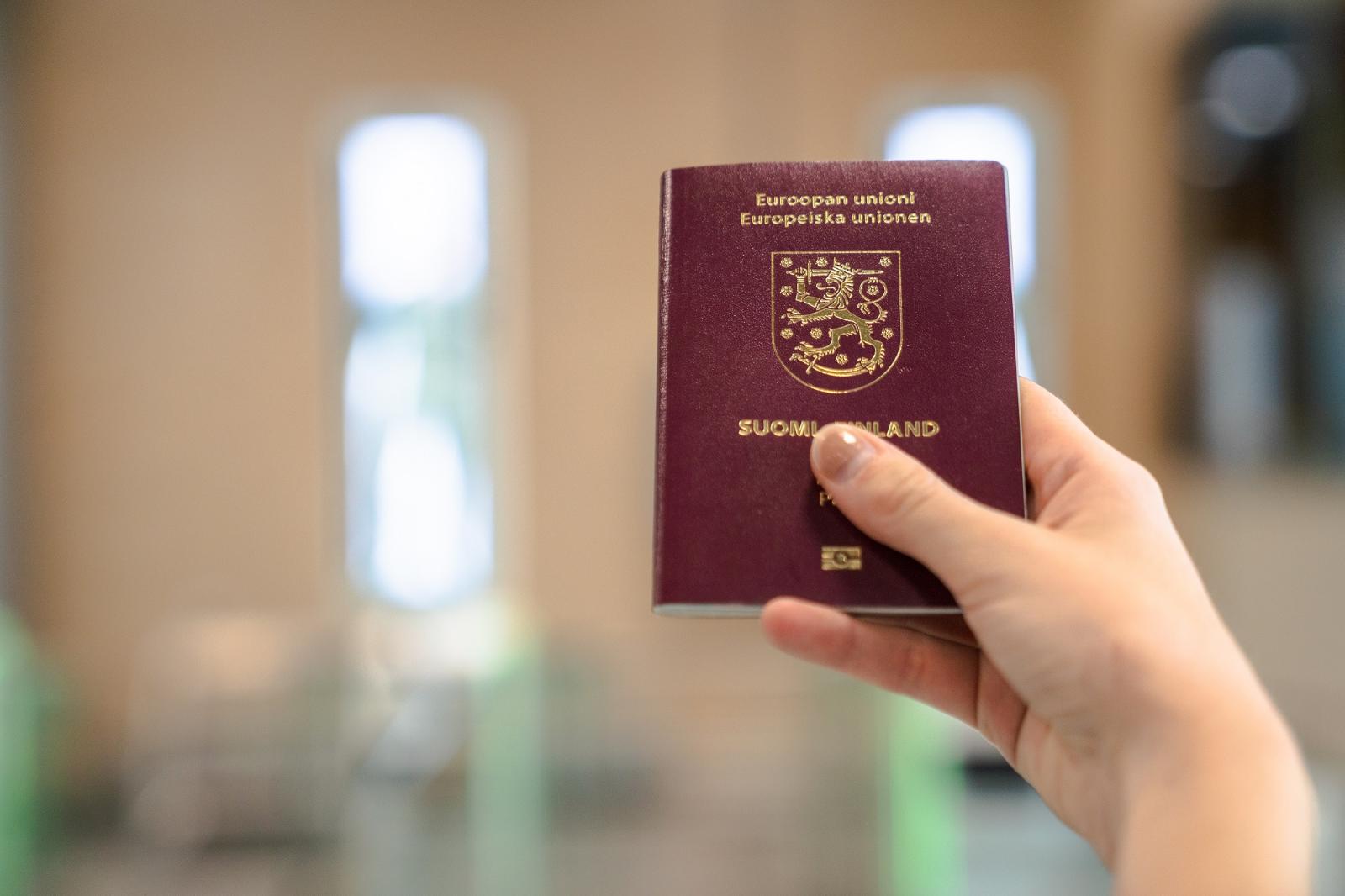 Henkilö pitää kädessään Suomen passia 