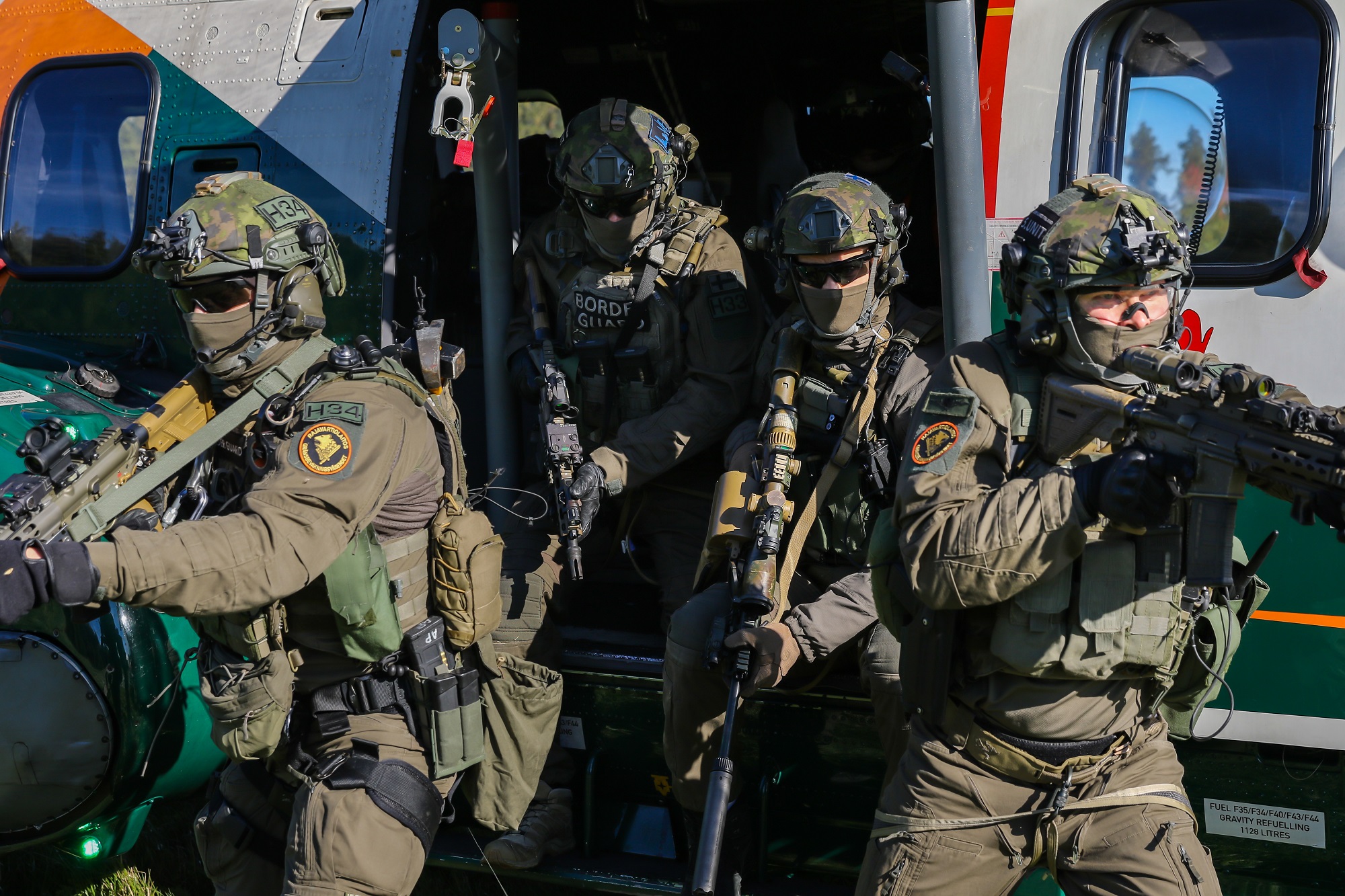 Neljä raskaasti varustautunutta sotilasta tulee ulos helikopterista.