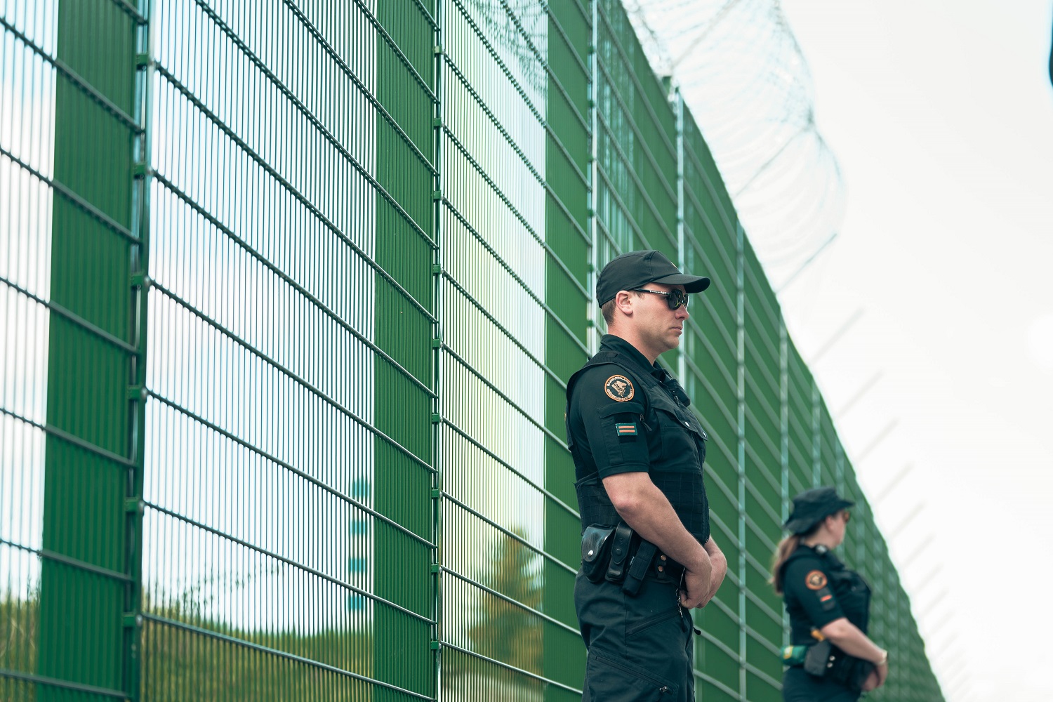 Vihreä esteaita jonka edessä seisoo kaksi rajavartijaa.