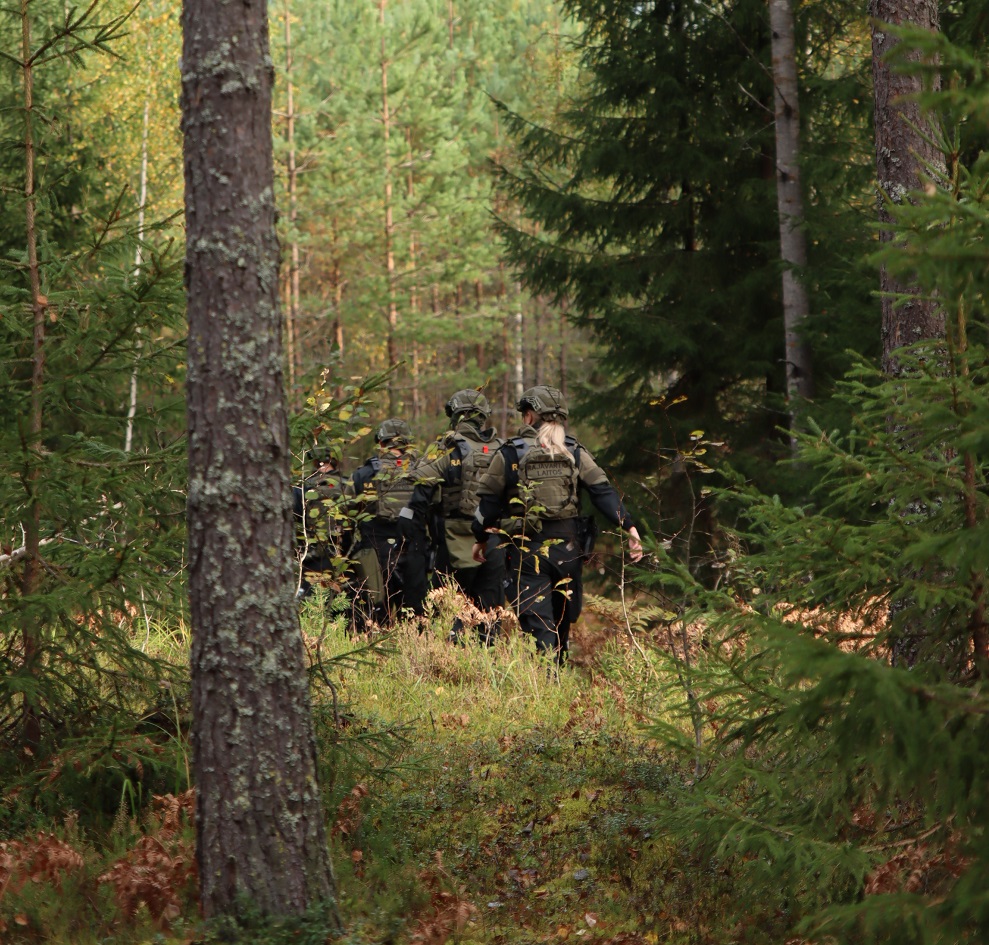 Ryhmä kävelee metsässä suojavarusteissa.